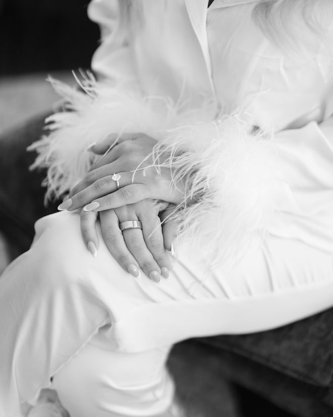 The bride places her hands on her knees showing off her wedding nails and engagement ring. 