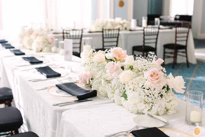 Wedding party reception table with black, white and emerald details and green and white lush flowers.