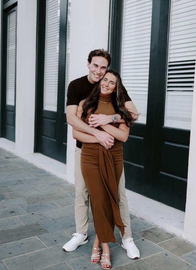 The groom stands behind the bride holding her hands outside The Tremont House.