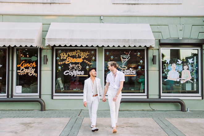 The two groom's hold hands outside a Houston reception where they are hosting their rehearsal dinner.