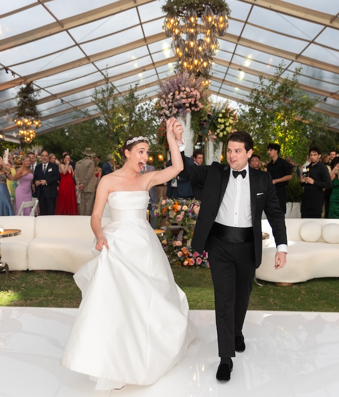 The bride and groom cheering as they walk on the dance floor. 