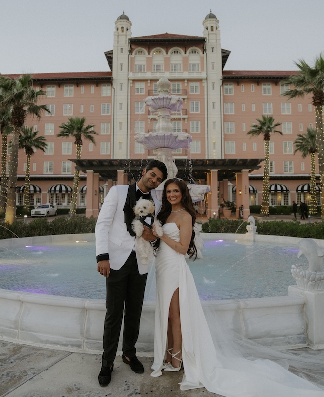 The bride and groom posing with their dog in front of the Grand Galvez. 