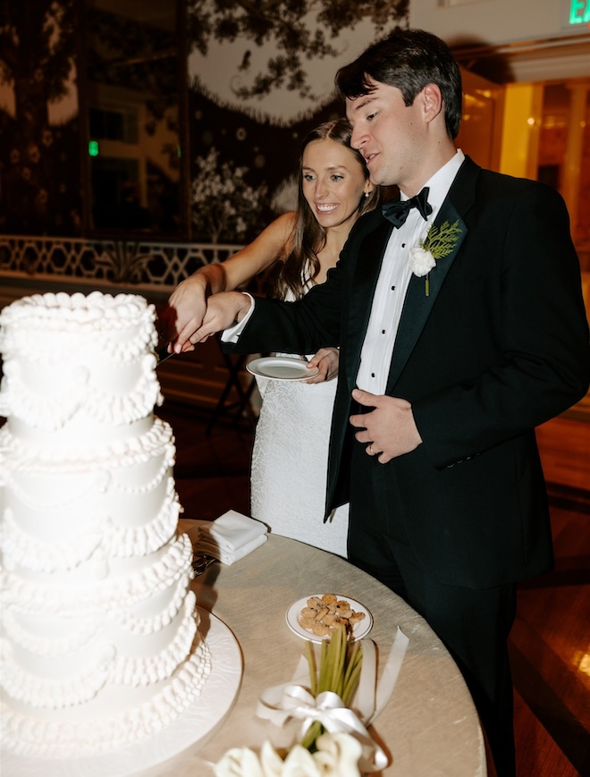 The bride and groom cutting into a vintage-style wedding cake. 