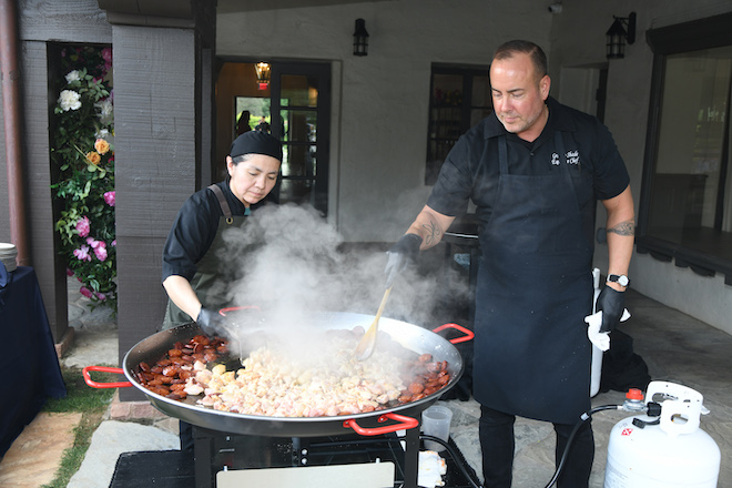 Two Masraff's workers cooking in a huge pan outside of venue for luxury multi-cuisine wedding catering. 