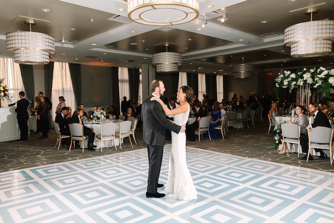 The bride and groom dance on a white and blue dance floor for blue wedding inspiration.