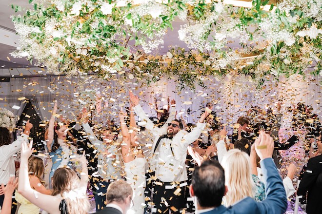 The couple and their guests cheering as gold confetti rains down on the dance floor. 