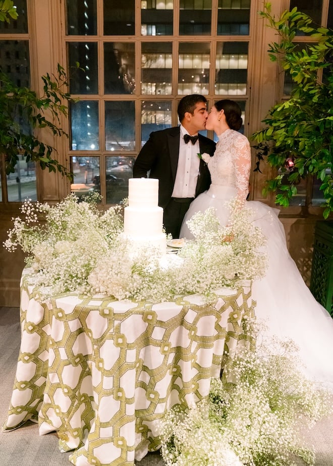 The bride and groom kiss behind their wedding cake at the Corinthian Houston.
