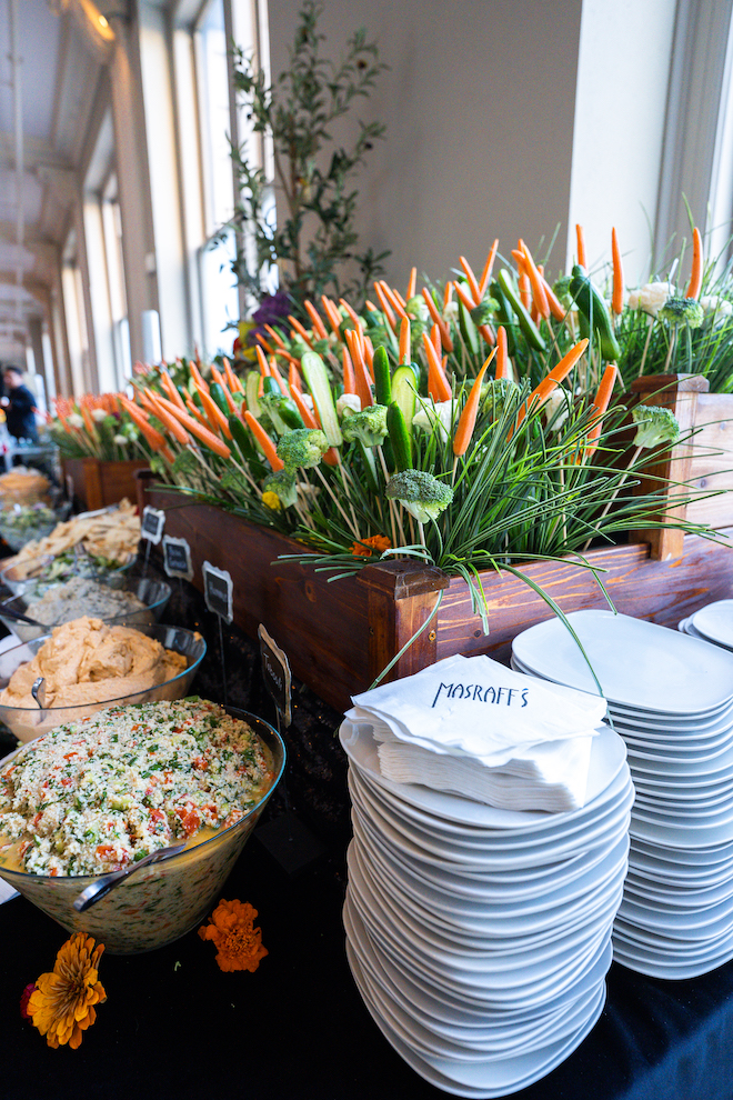 Luxury multi-cuisine wedding catering set up different dips with broccoli and carrot plant decor behind it.