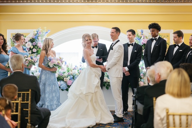 The bride and groom hold hands during their wedding ceremony at a Houston hotel. 