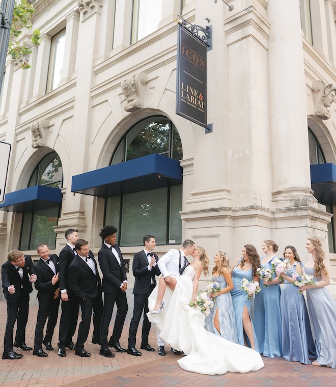 The bride and groom share a kiss outside Hotel ICON as the wedding party celebrates around them. 