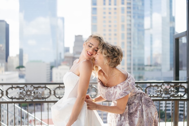 The mother of the bride helps her daughter into her wedding gown on the terrace of the Hotel ICON's penthouse in downtown Houston. 