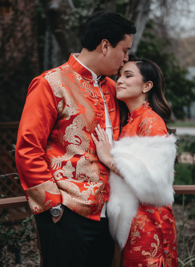 The groom kissing the brides forehead as they wear traditional Asian tea ceremony attire. 