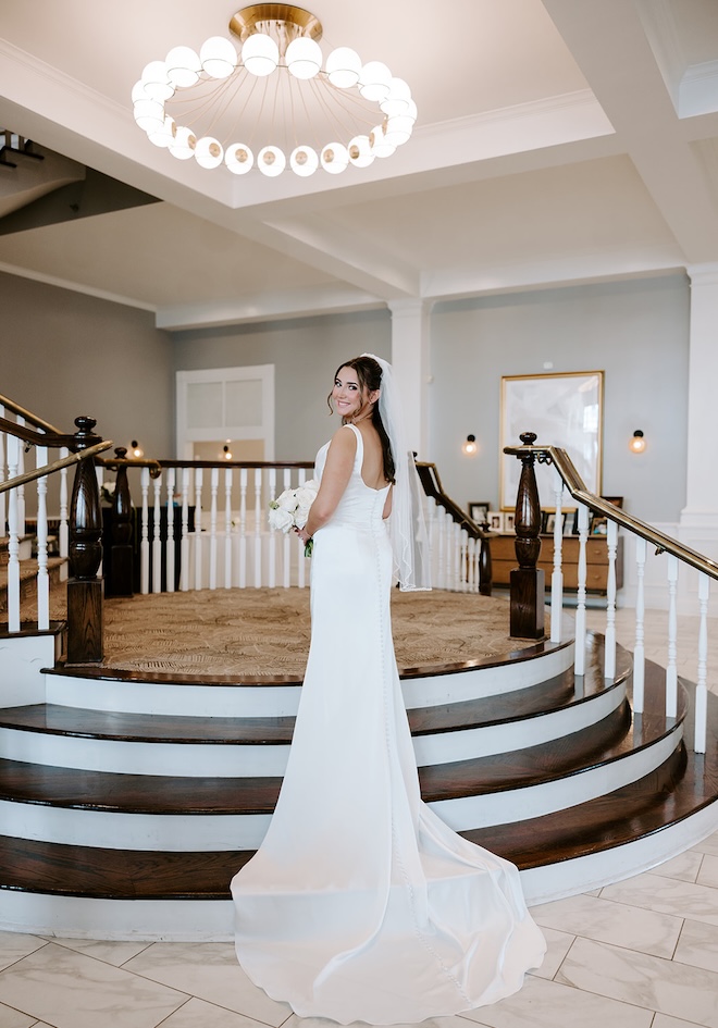 The bride stands on the grand stair case of The Tremont House's ballroom.