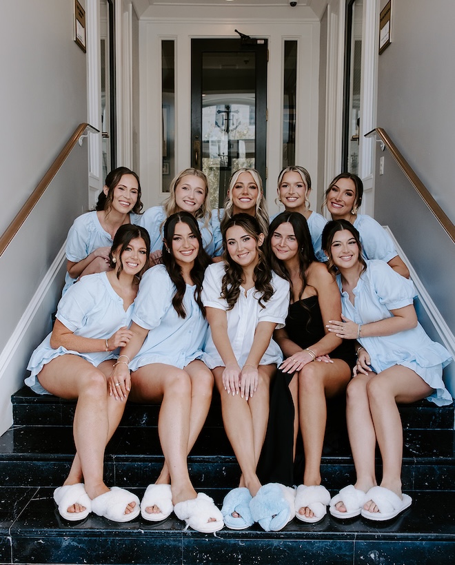 The bride and her bridesmaids sit on the steps of The Tremont House. 