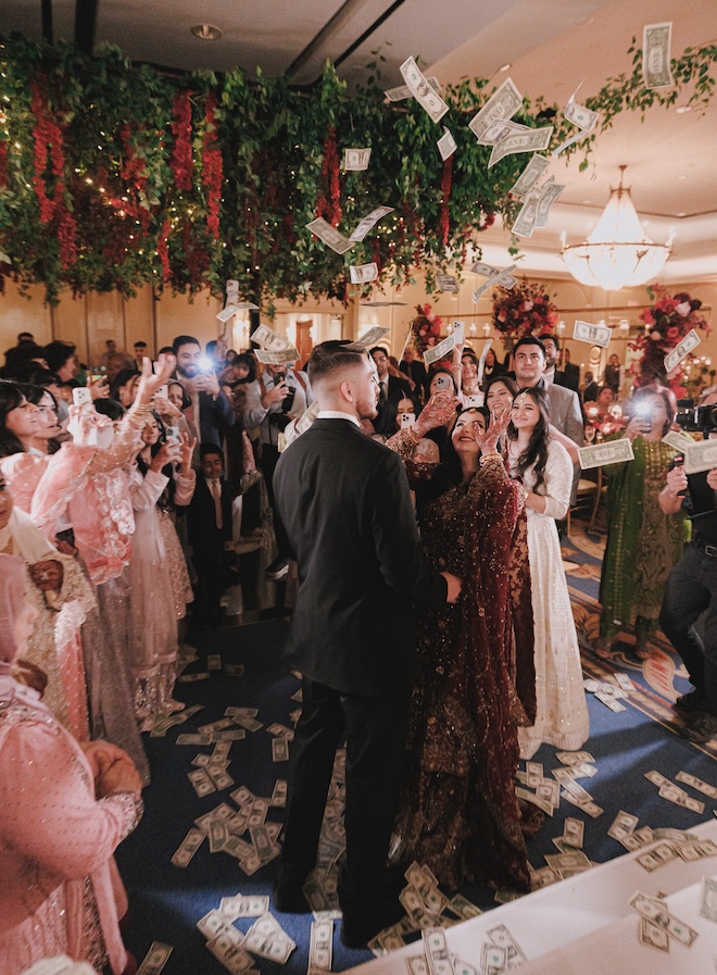 Dollar bills being thrown into the air at the Beauty and the Beast-inspired wedding reception. 