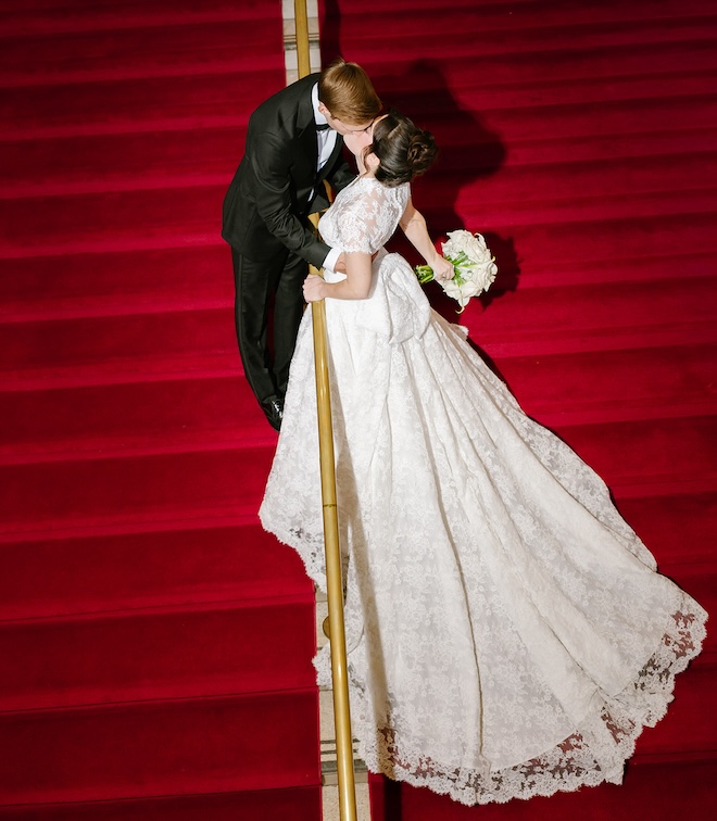The bride and groom kissing on the red stairs at the Corinthian Houston. 
