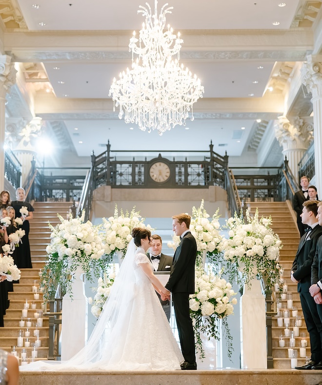 The bride and groom holding hands at the altar as her brother officiates. 