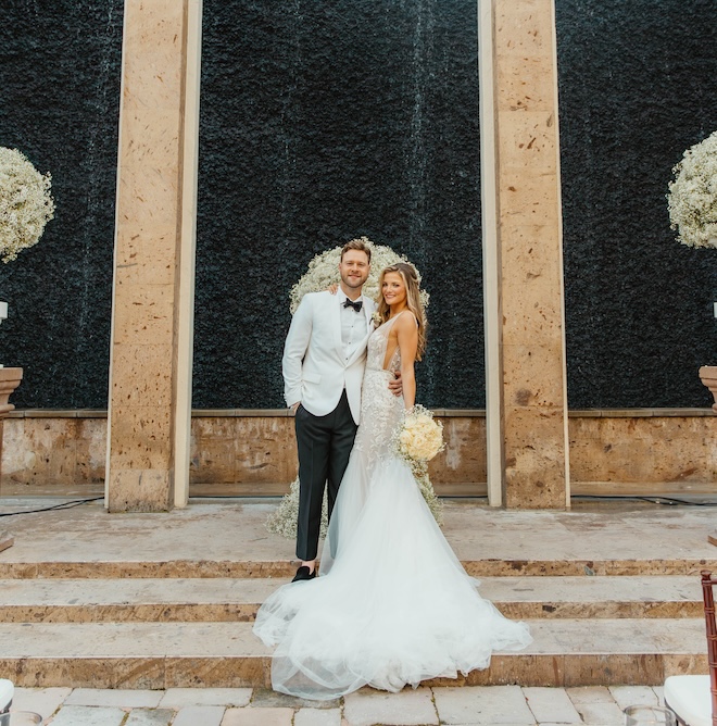 The bride and groom smiling in front of the water wall at The Bell Tower on 34th. 