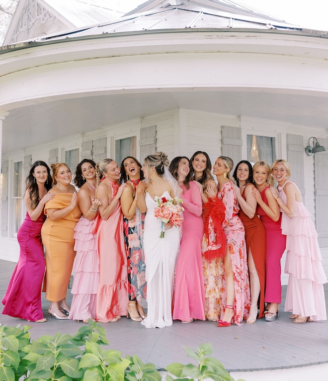 The bridesmaids wear colorful dresses that are pink, orange and red for the couple's spring wedding. 