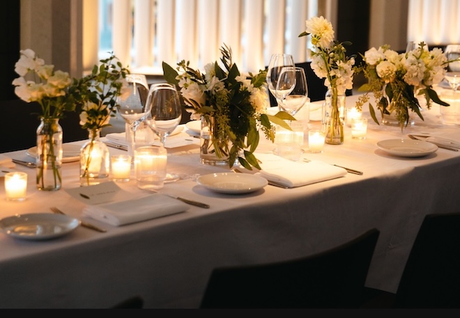 White flowers, greenery and tea lights decorate the family-style table at Soleil. 