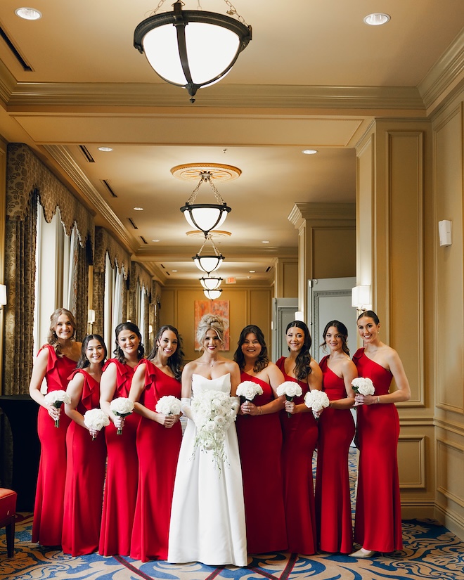 The bridesmaids wear red one-shoulder gowns for the Houston ceremony. 