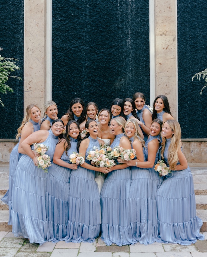 The bridesmaids hug the bride at her outdoor wedding ceremony in Houston. 