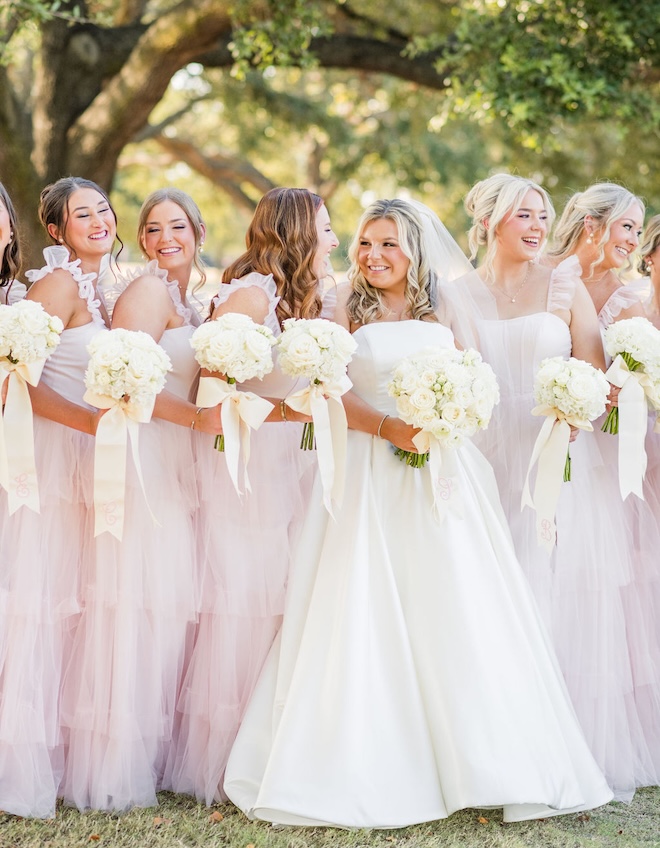 The bridesmaids wear light pink ruffled wedding dresses for a country club wedding in Houston.