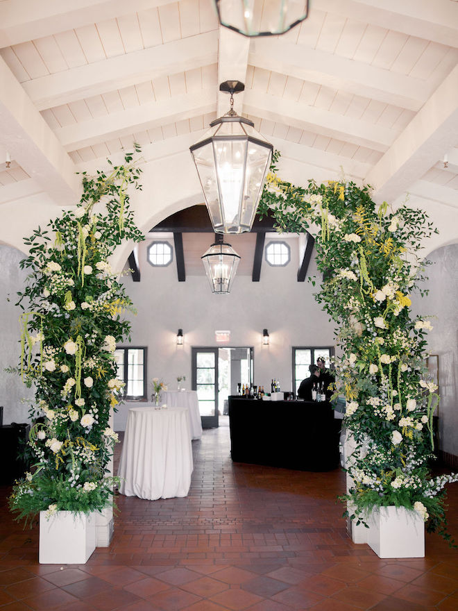 Lush greenery arches with yellow and white florals inside reception venue for dreamy yellow outdoor wedding.