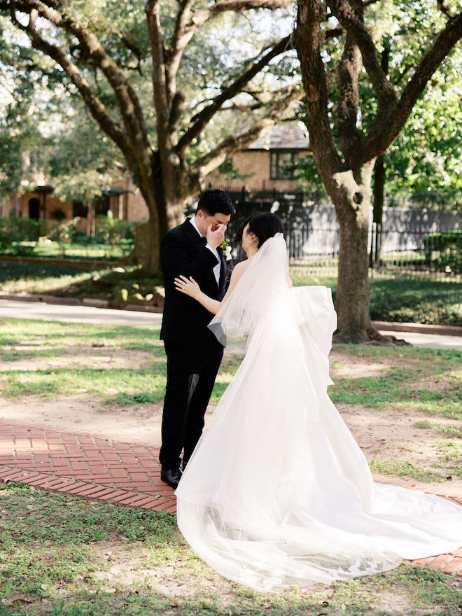 Bride smiling and laughing while groom sheds a tear during their first look.