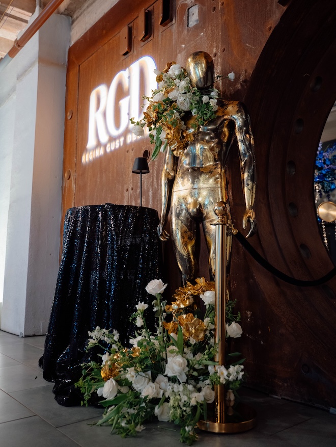 Gold statue decorated with florals in front of The Vault. 