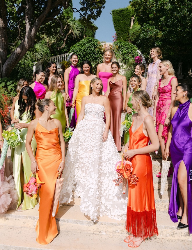 The bridesmaids wear vibrant dresses next to the bride.