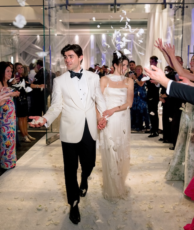 The bride, Blayne Fertitta and the groom holding hands during their grand exit with a white petal send off. 