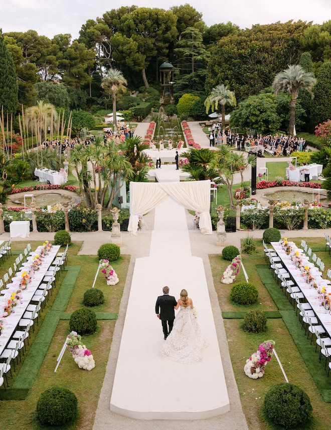 The father of the bride walks the bride down the aisle to their French Garden wedding.