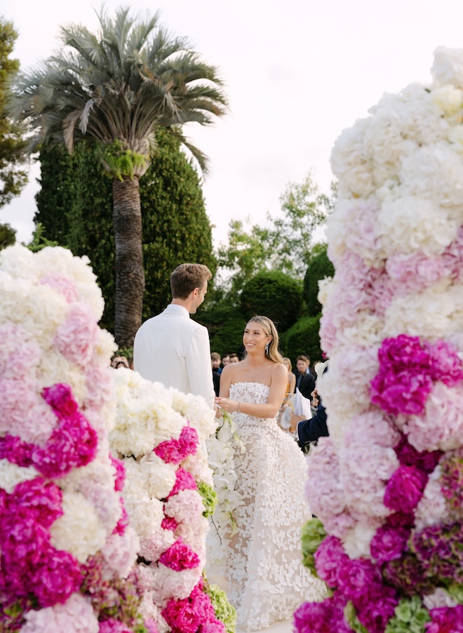 The bride and groom hold hands at the alter at their vibrant French Riviera wedding.
