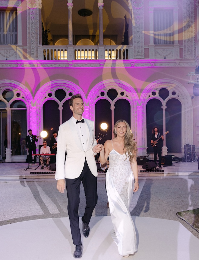 The bride and groom hold hands on the dance floor of their vibrant French Riviera wedding.