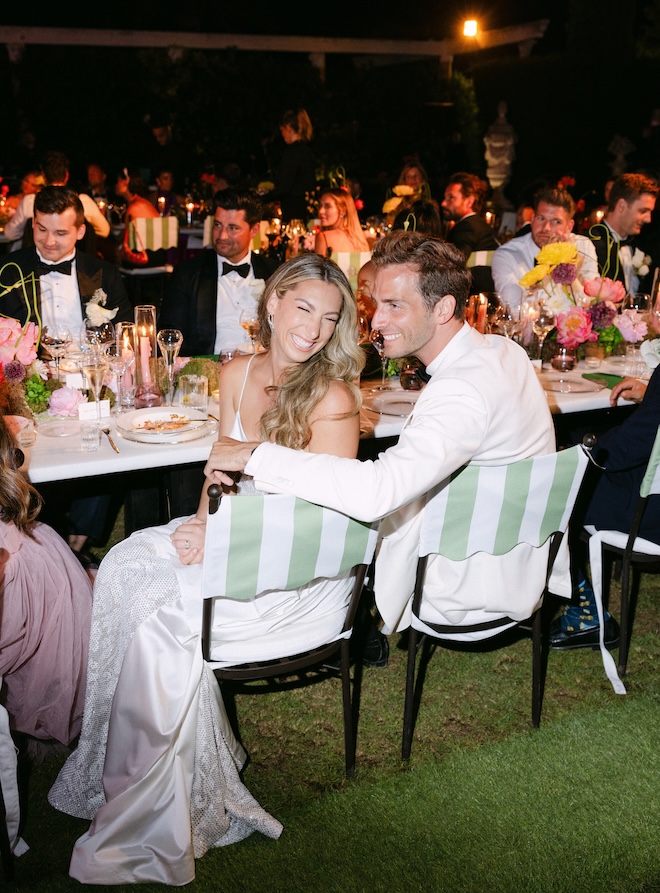 The bride and groom smile at their outdoor wedding reception.