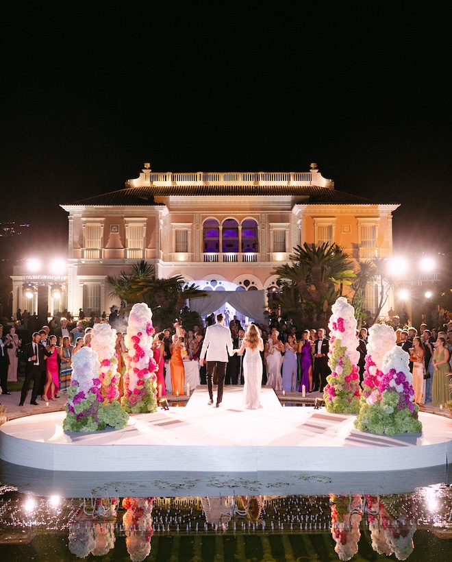 The bride and groom hold hands as they walk off the dance floor. 