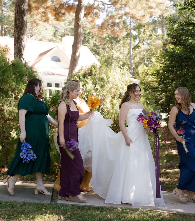 The bride and her bridesmaids walking together with their bouquets. 