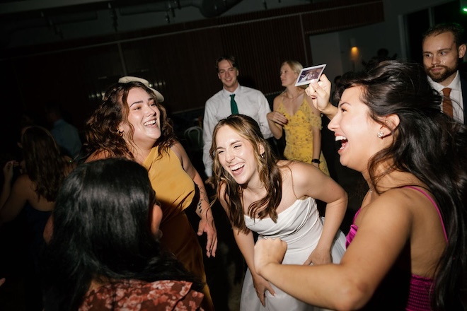 The bride laughing and dancing with her friends.