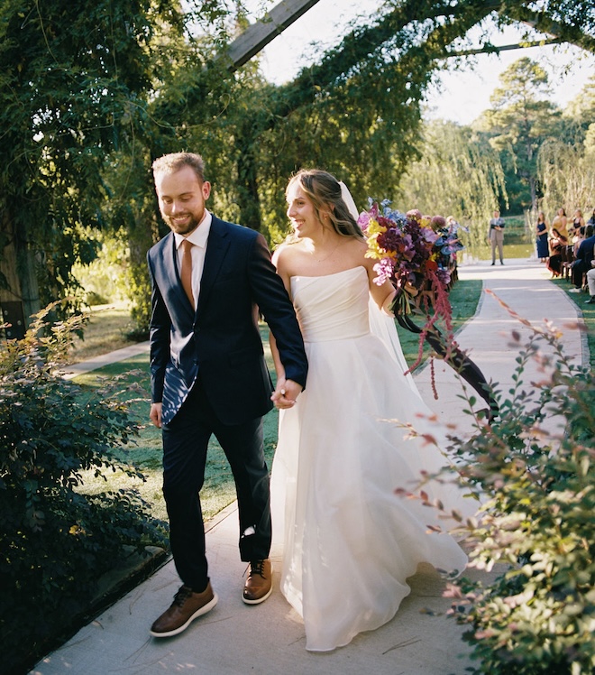The bride and groom smiling and holding hands walking back down the aisle. 