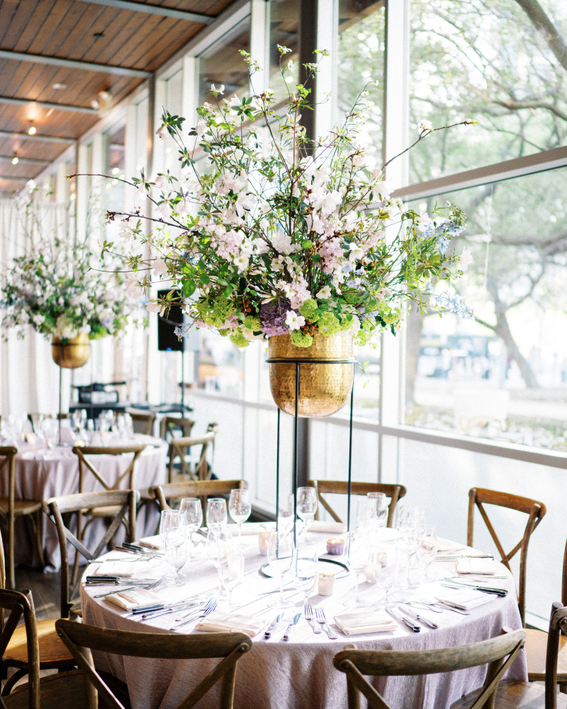 Tall green and light purple floral centerpieces at top Houston restaurant wedding venues The Grove.