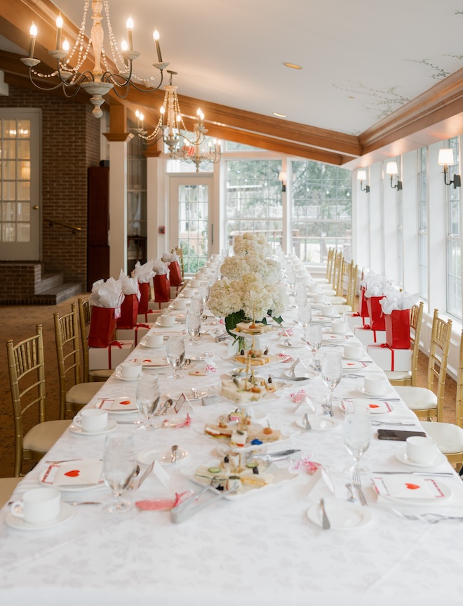 A long table decorated with white hydrangeas, tea sandwiches, and red and white stationery at the Manor House at The Houstonian Hotel, Club & Spa. 