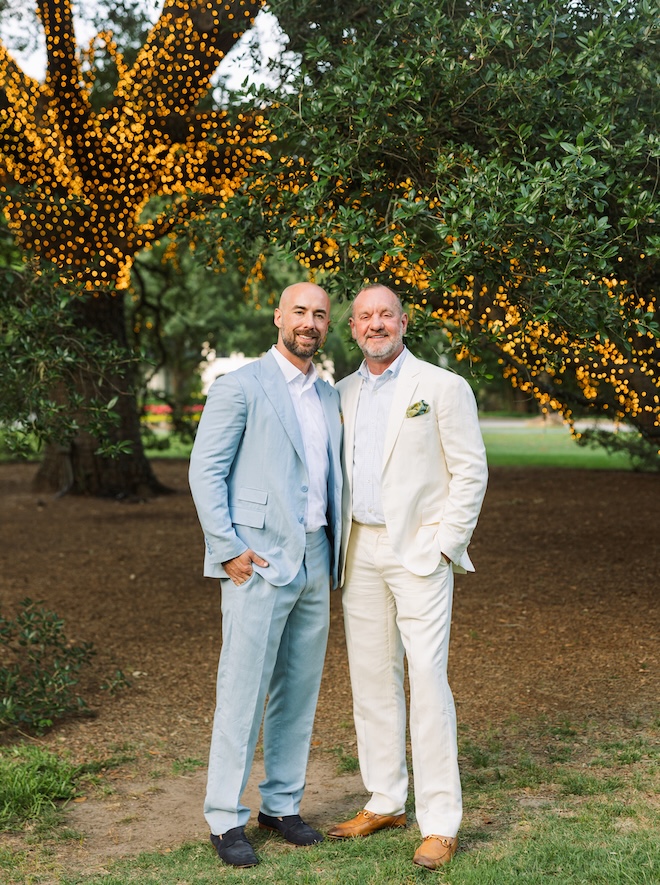 The two grooms stand under the oak tree at The Houstonian Hotel, Club and Spa.