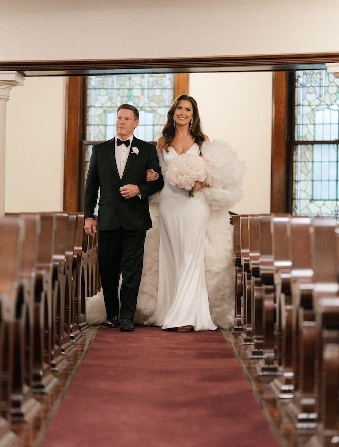 The father of the bride walks his daughter down the aisle at the church ceremony.