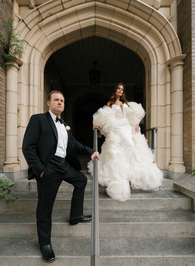 The bride and groom stand on the stairs outside of a Houston church. 
