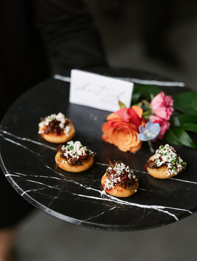 Mini bites on black plate and roses being served from luxury Houston wedding catering by Cafe Natalie.