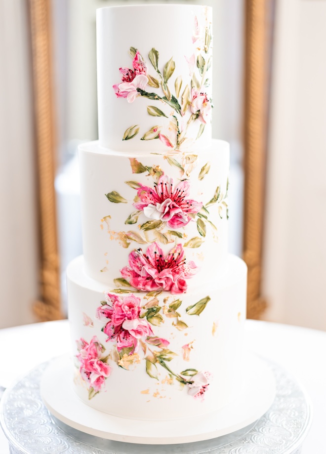 A three-tier white cake with a pink and green floral print. 