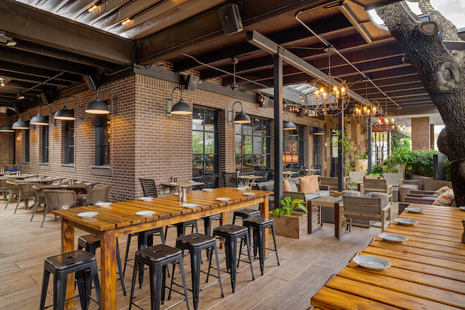 Outdoor patio with industrial lights, metal chairs, and wooden tables bringing a modern look to this top Houston restaurant venue.