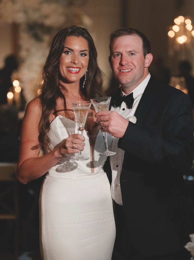The bride and groom cheers Champagne glasses at their Houston ballroom wedding at Thompson Houston, by Hyatt.