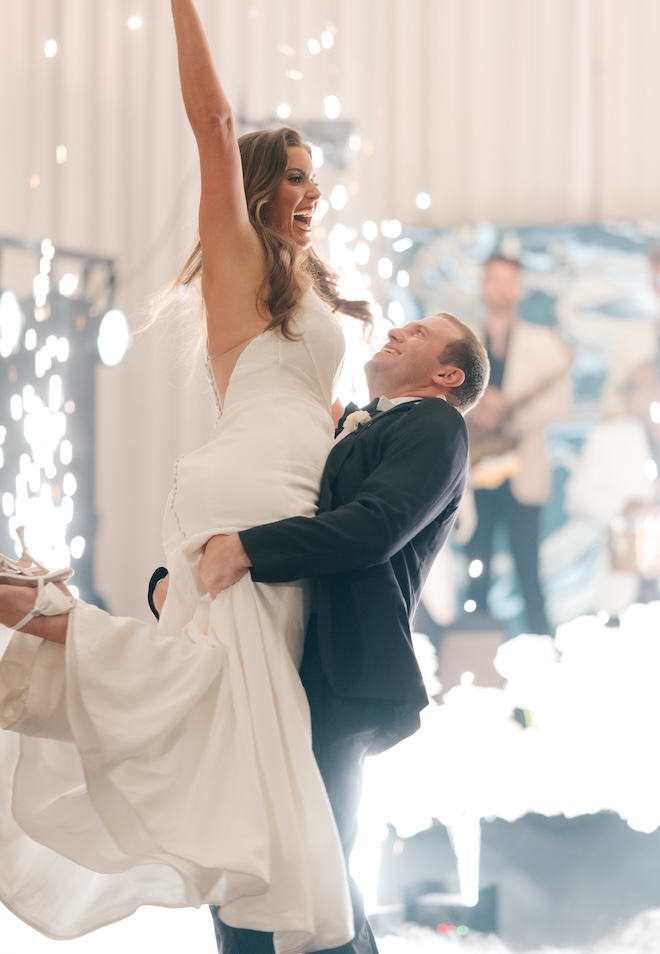 The groom picks up the bride on the dance floor at their reception. 